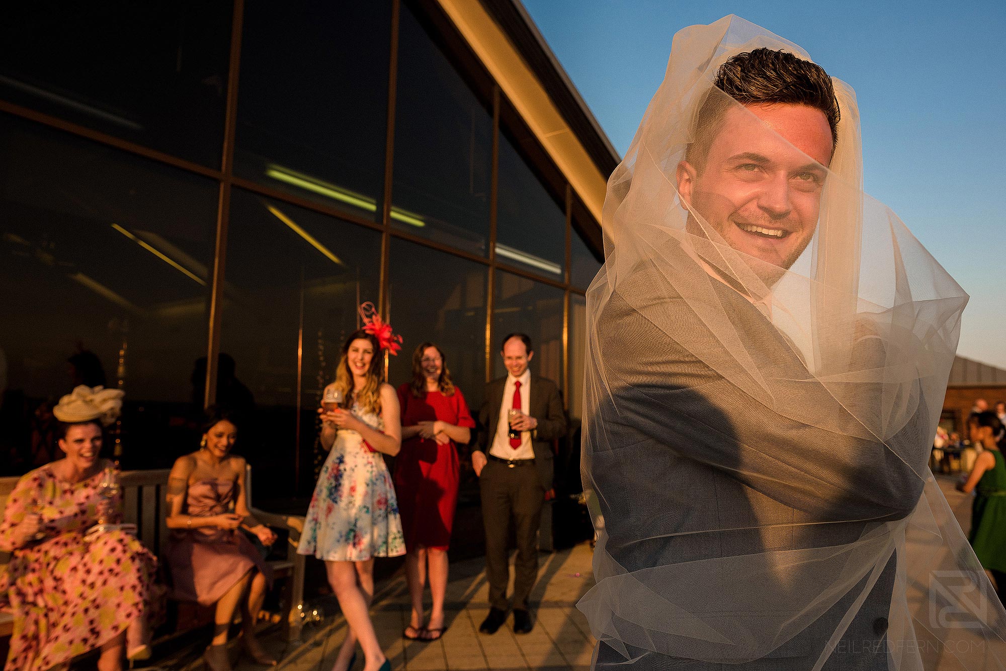 wedding guests having fun with bride's veil