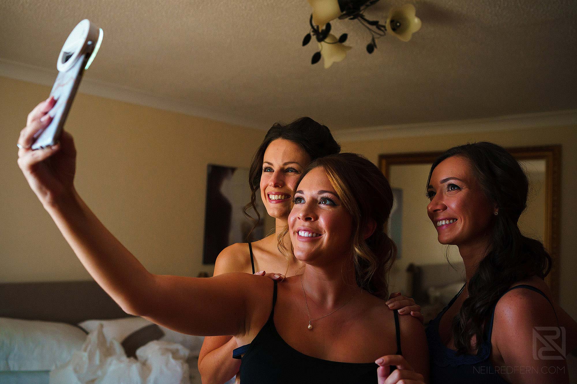 bridesmaids taking selfie photograph on morning of wedding