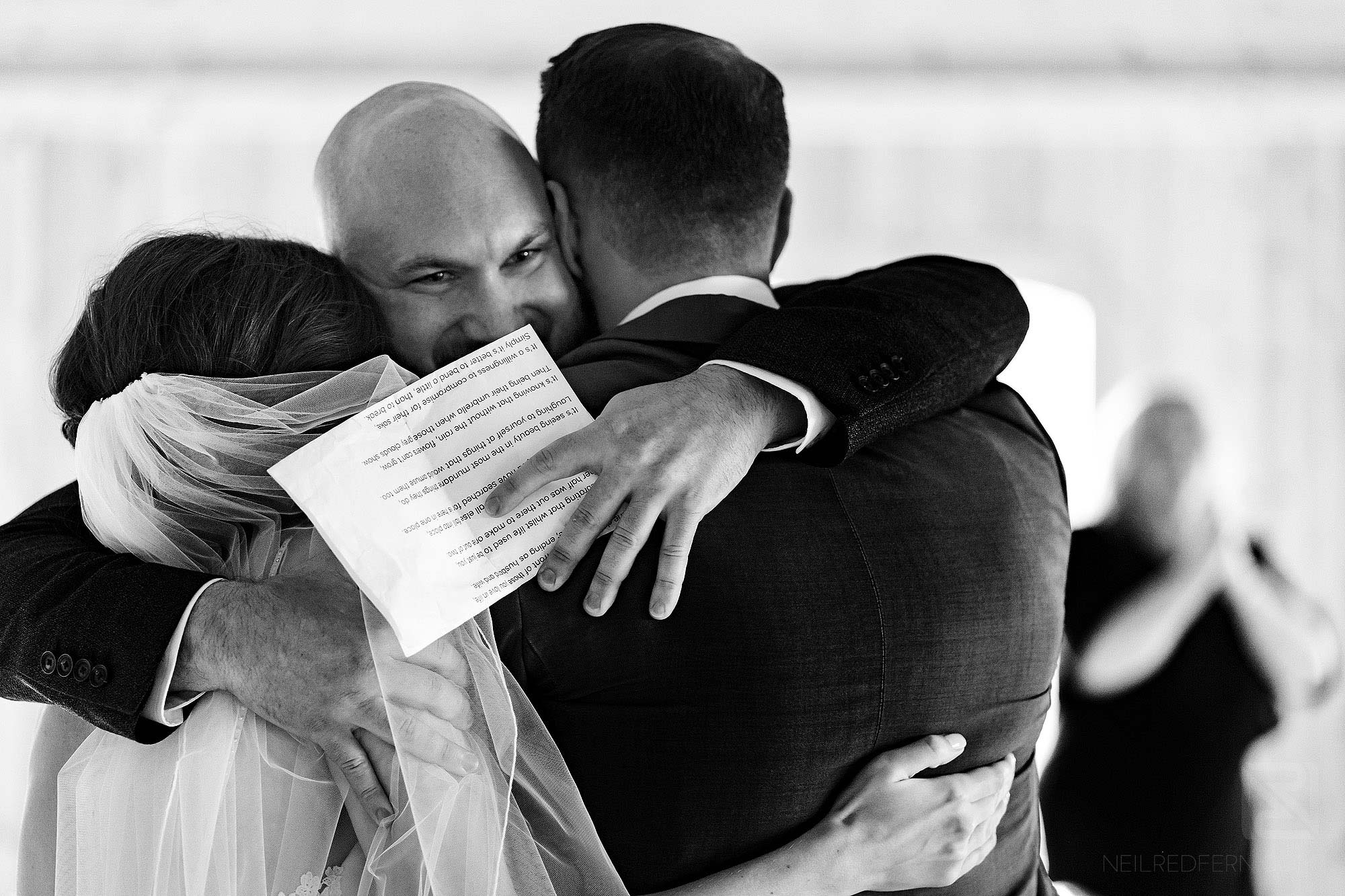 friend hugging newlyweds during wedding serivce