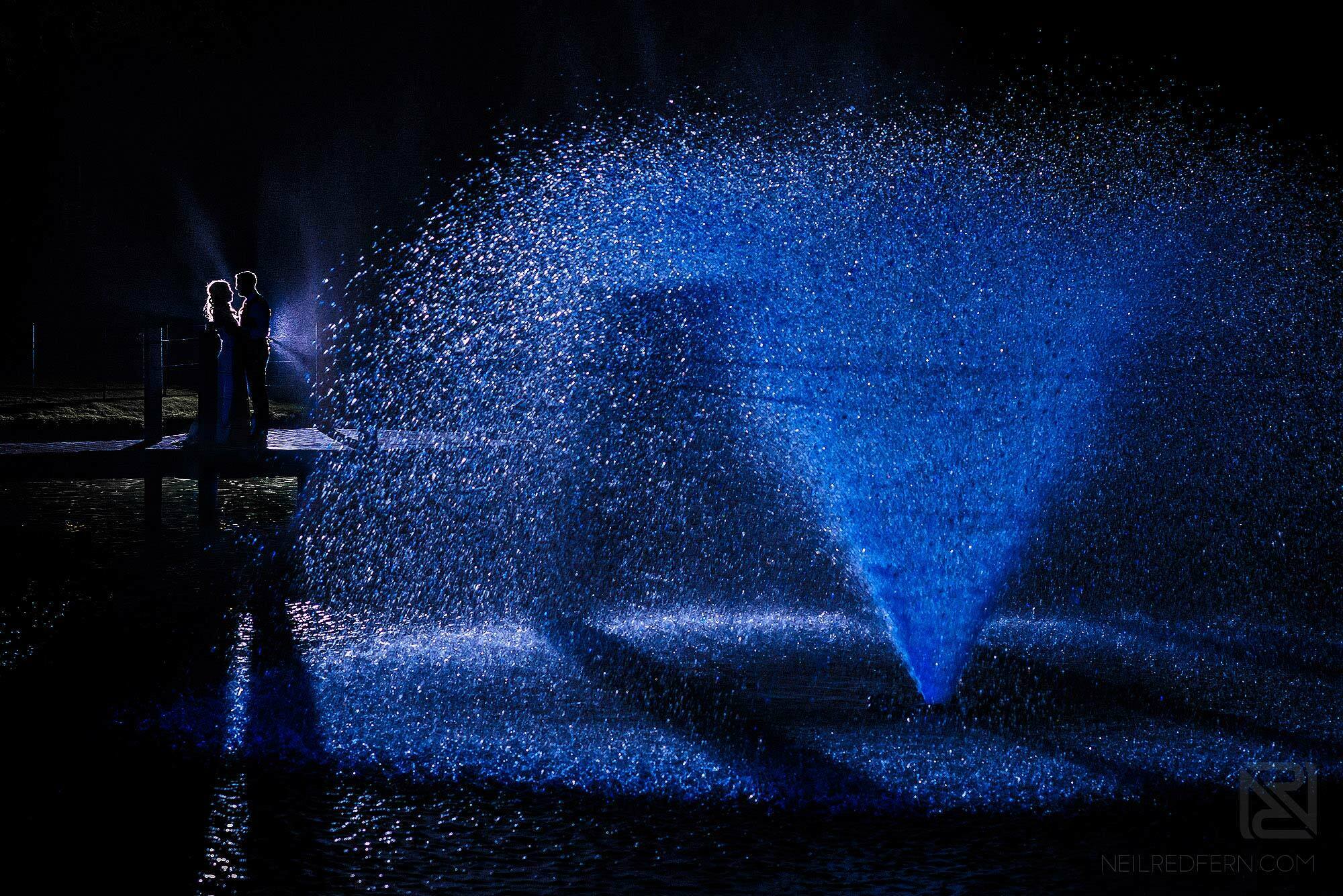 creative off camera flash portrait bride and groom in front of fountain