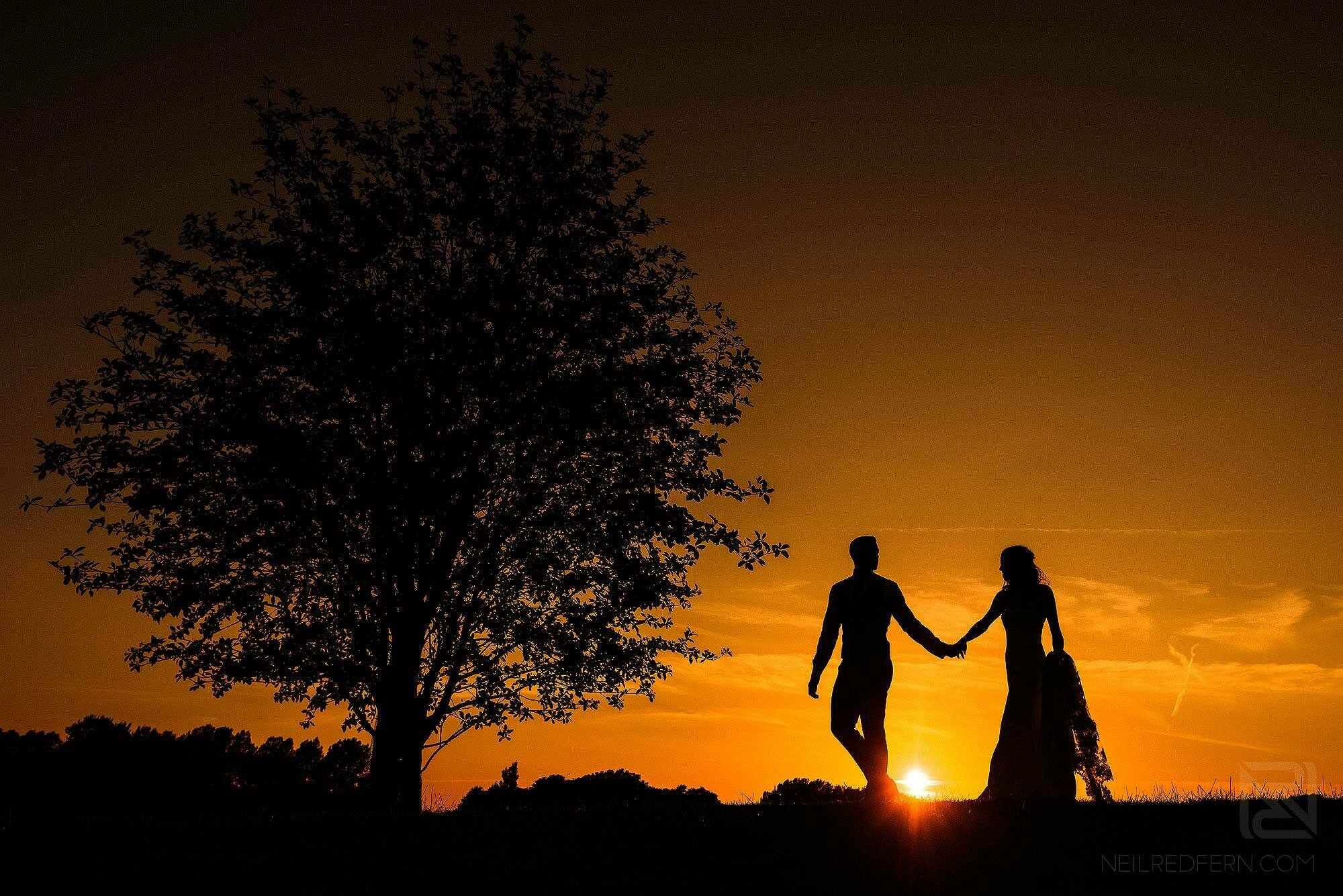 silhouette photograph of bride and groom at sunset