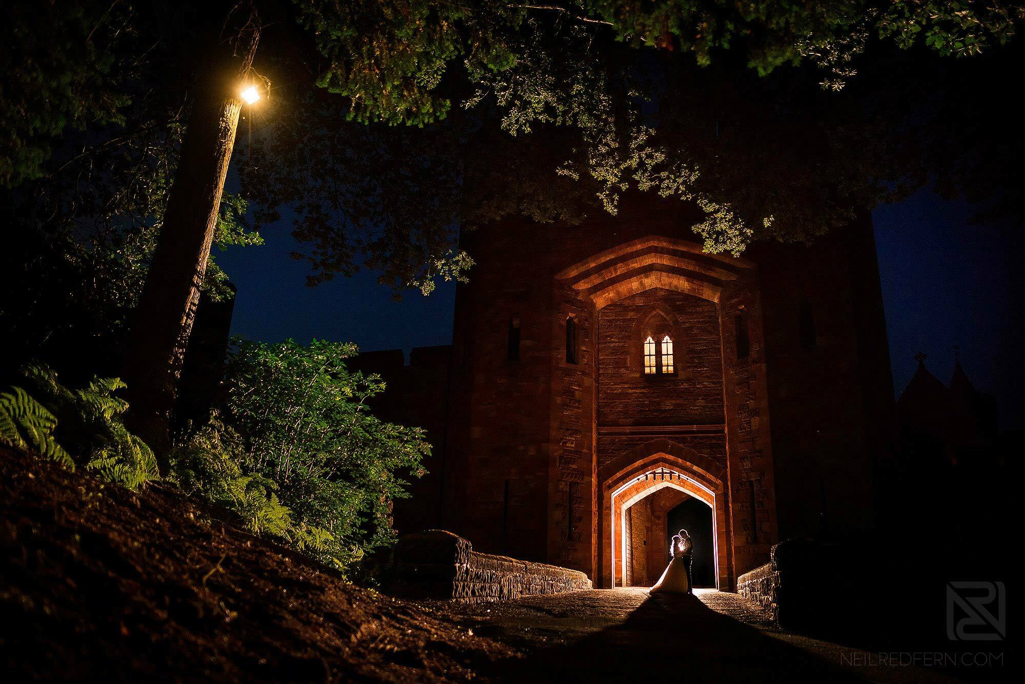 night time photograph of bride and groom outside Peckforton Castle in Cheshire
