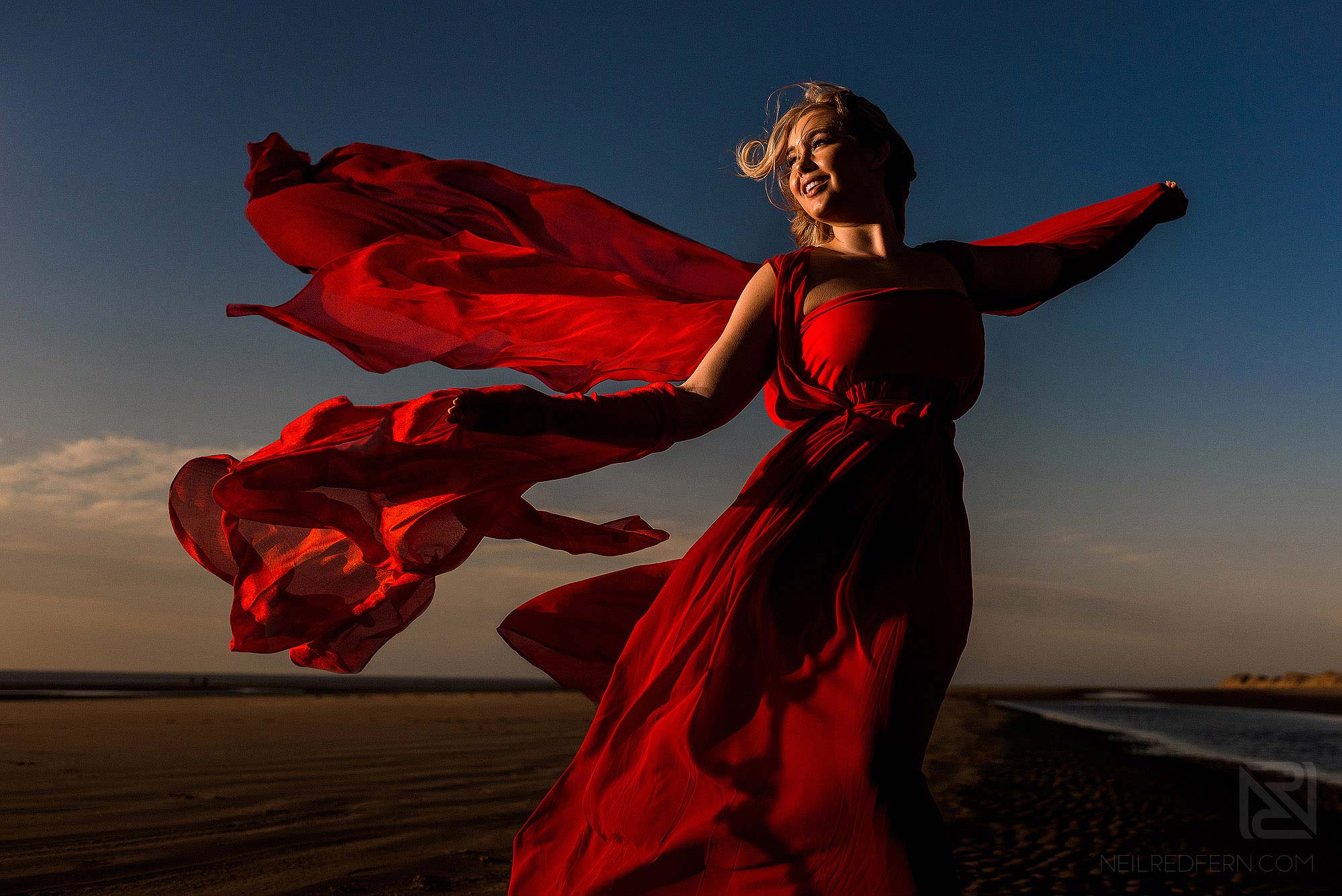 bride with flowing red dress on the beach