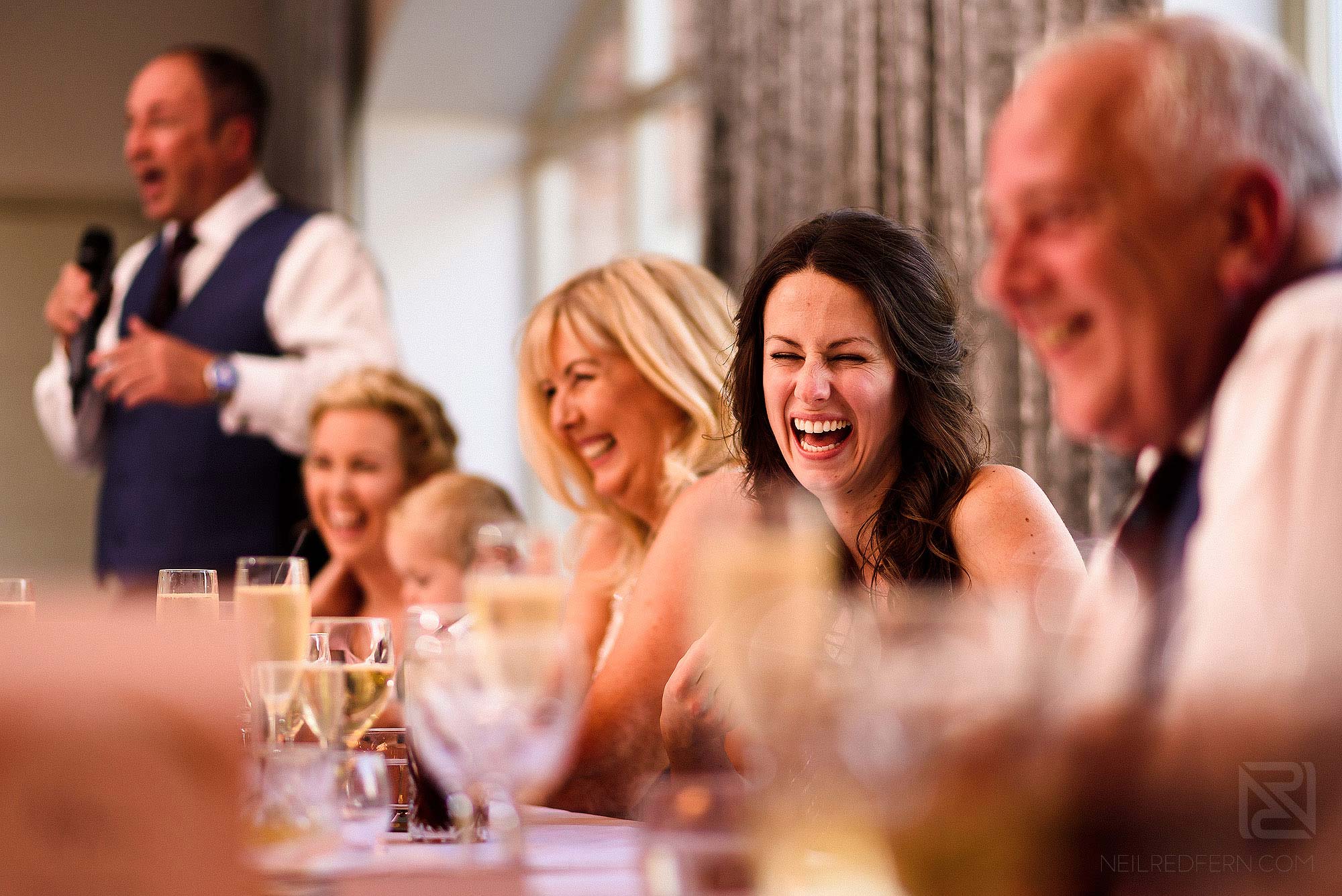 bride smiling during father's speech at wedding