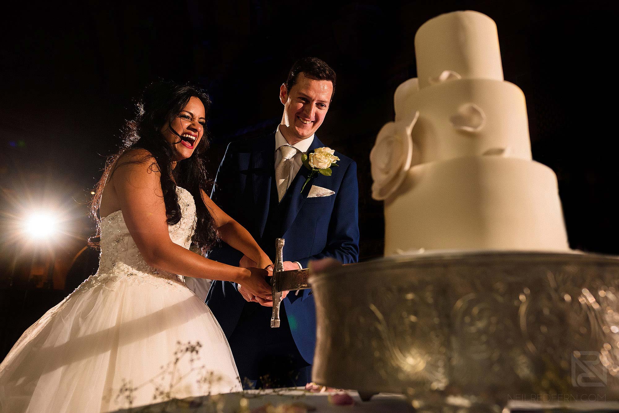 bride and groom cutting wedding cake with sword