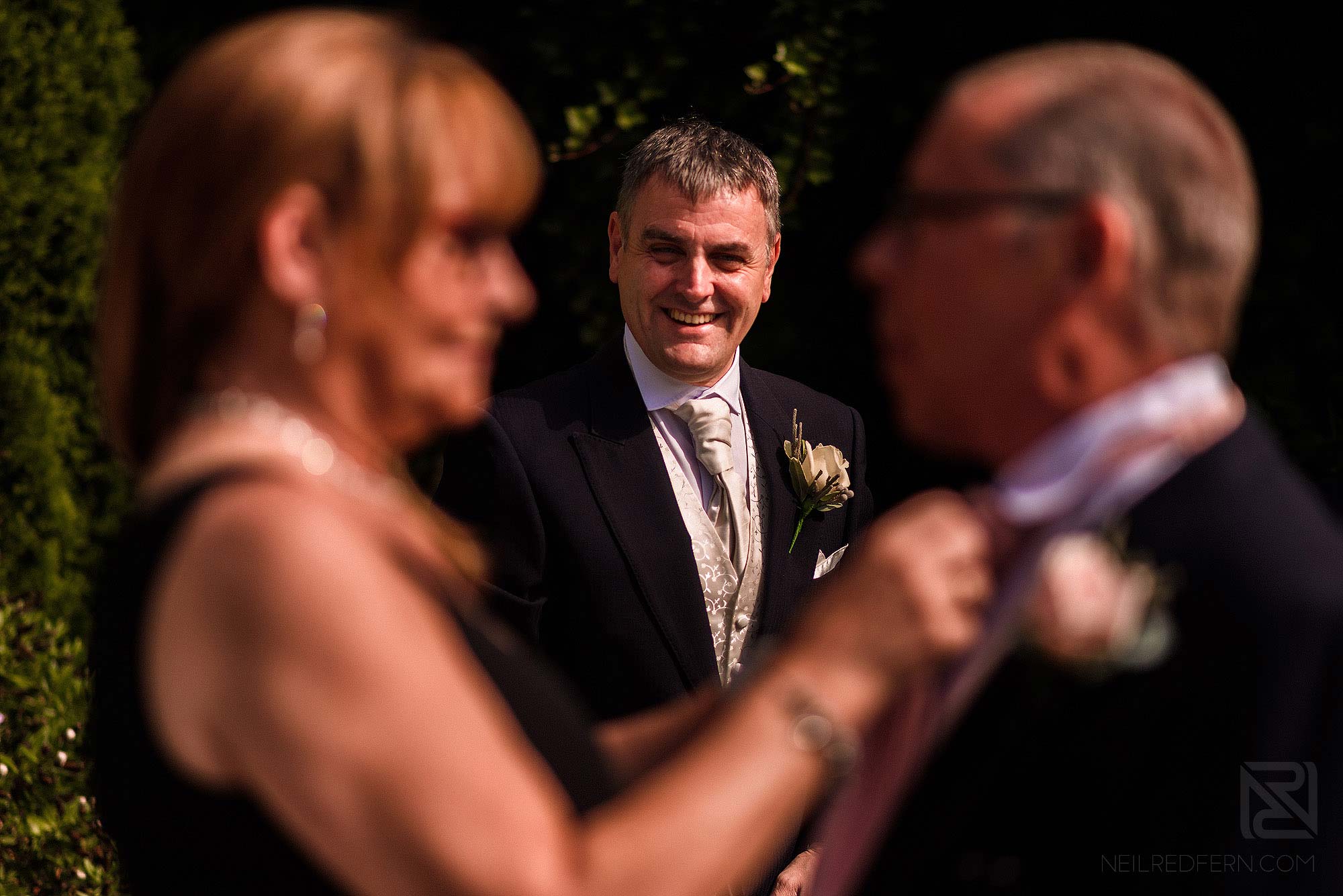 groom and best man putting on wedding flowers