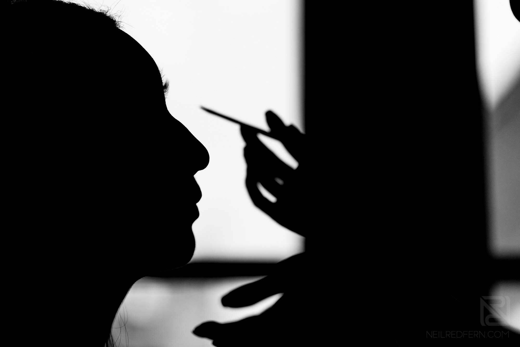 silhouette photograph of bride having make-up put on